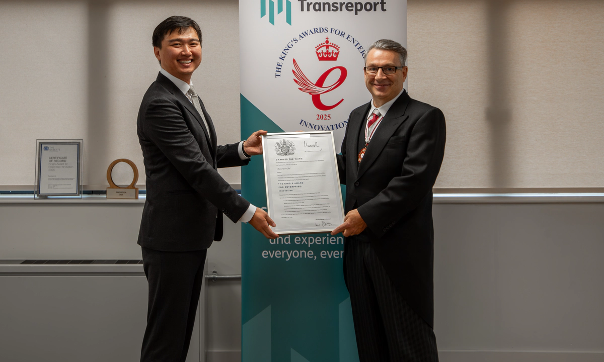 Photo of Jay Shen and Mr Kevin McGrath OBE MRICS DL smiling, holding the official King’s Award certificate together. They stand in front of the Transreport King’s Award for Enterprise in Innovation banner. Photo of Jay Shen and Mr Kevin McGrath OBE MRICS DL smiling, holding the official King’s Award certificate together. They stand in front of the Transreport King’s Award for Enterprise in Innovation banner.