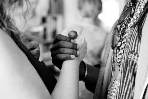 A zoomed-in black and white photograph of a black and white woman holding hands