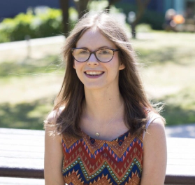 Chloe Tear, a white woman with brown hair and black glasses facing and smiling to the camera