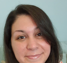 Victoria, a woman with long, dark hair wearing a white top with red, blue, yellow, and pink horizontal stripes across it, smiling at the camera.