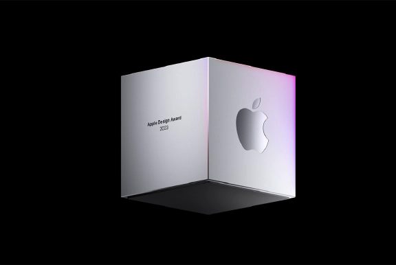 一方の面にはアップルデザインアワード 2023の文字が、もう一方の面にはAppleのロゴが描かれ、黒い背景に浮かぶ銀色の立方体。