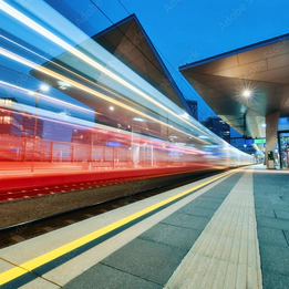 Photo of a red train speeding past a platform with a blur effect to convey movement. Photo of a red train speeding past a platform with a blur effect to convey movement.