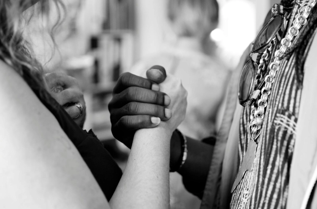 A zoomed-in black and white photograph of a black and white woman holding hands