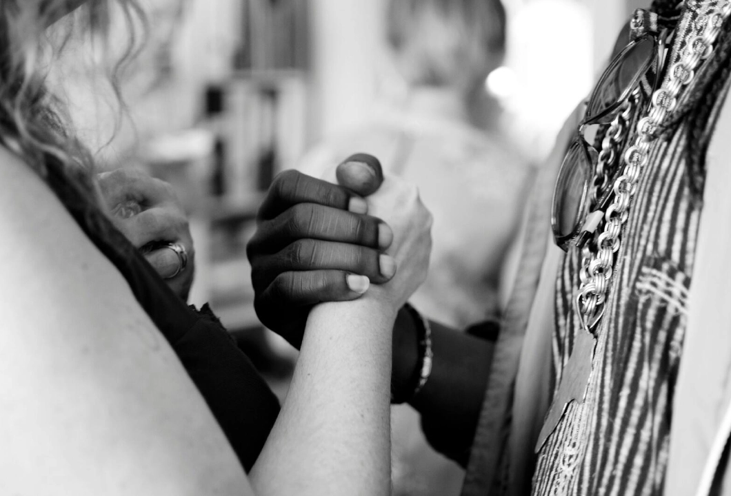 A zoomed-in black and white photograph of a black and white woman holding hands