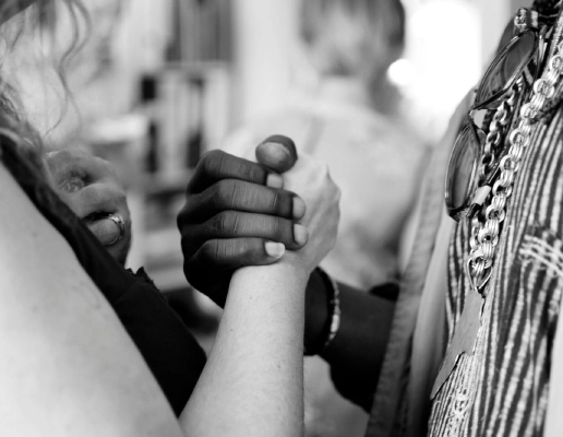 A zoomed-in black and white photograph of a black and white woman holding hands