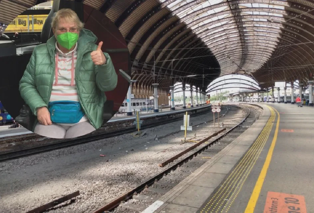 誰もいない駅のホームの写真の上に重ねられた、マスクをして親指を立てた年配の女性の写真