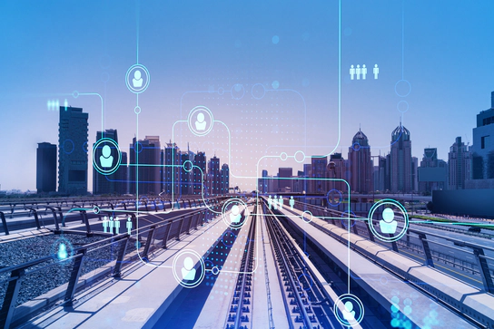 A railway track leading into a city skyline, overlayed with a graphic of an inter-connected matrix of people icons. A railway track leading into a city skyline, overlayed with a graphic of an inter-connected matrix of people icons.