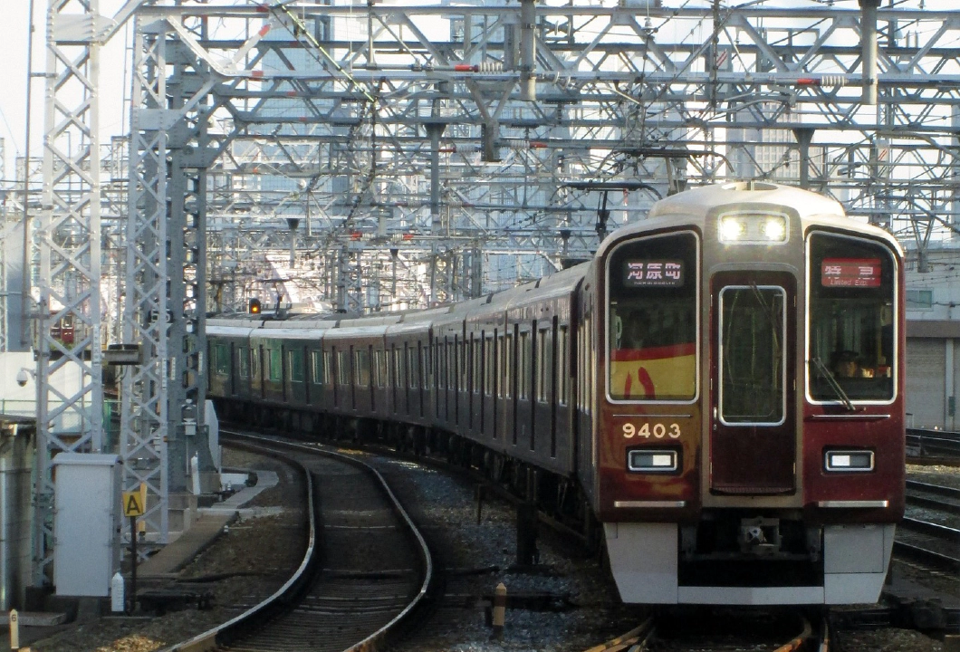 A picture of a dark red Hankyu train on the tracks at Osaka Railway Station.