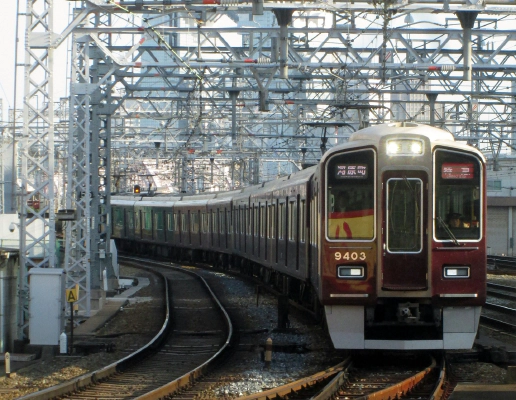 A picture of a dark red Hankyu train on the tracks at Osaka Railway Station.