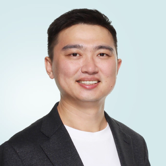 Jay Shen, an asian man with short black hair, and CEO of Transreport, smiling and facing the camera wearing a white t-shirt and black blazer.