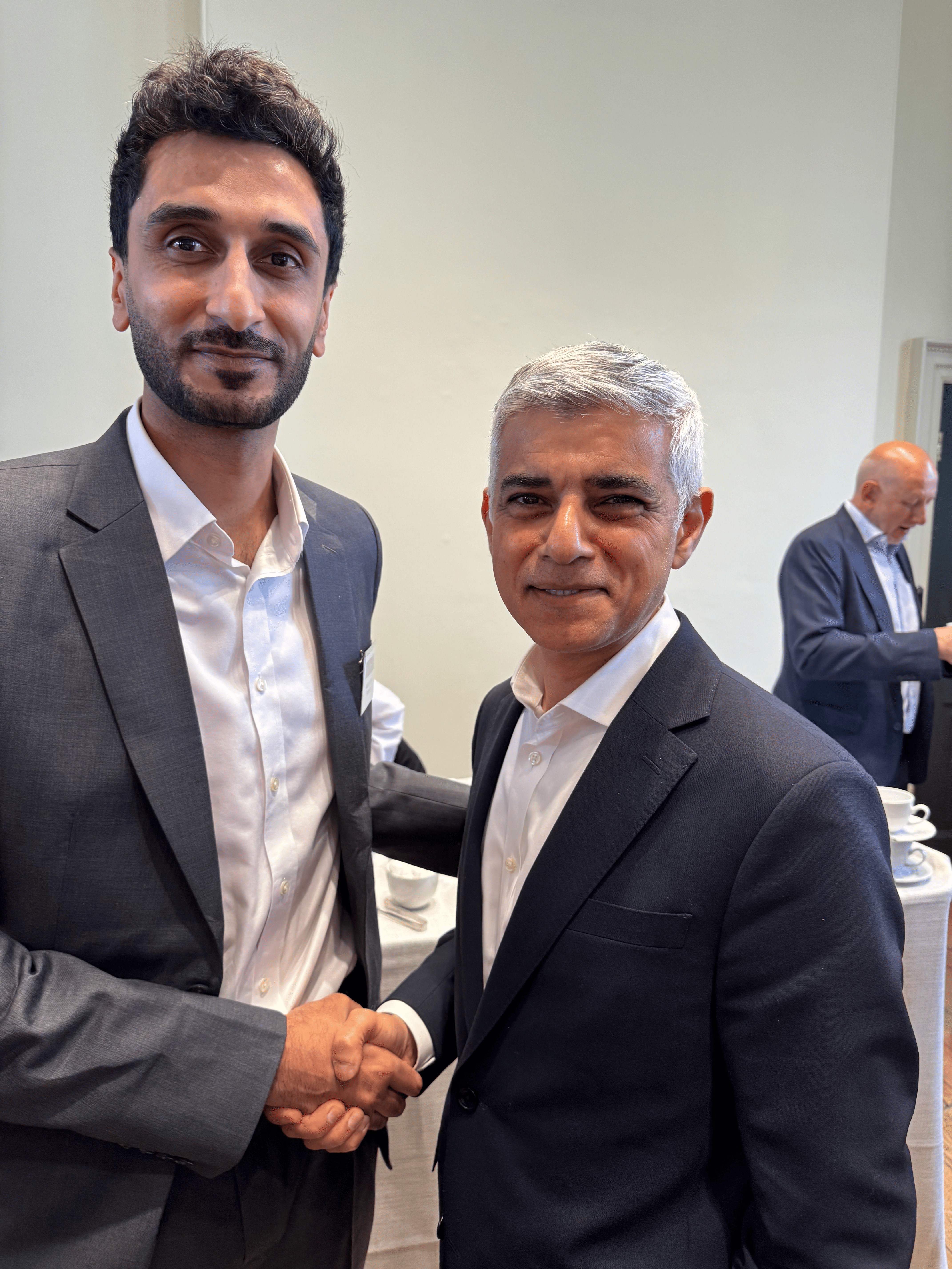 Waleed Ahmed, Transreport COO, and Sadiq Khan. Both are smiling at the camera and shaking hands.