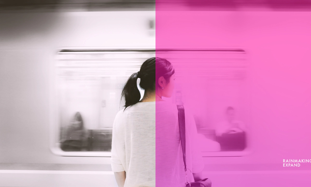 A woman standing on a platform facing a moving train.