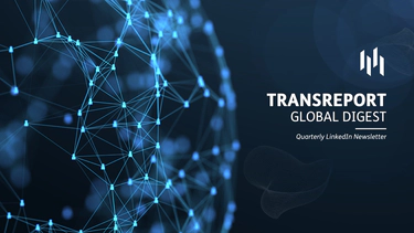 A red and black commercial passenger train, stood stationary at a train platform, overlayed with a white version of the Transreport logo.